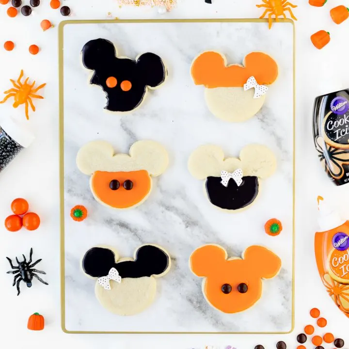 Mickey and Minnie Halloween Cookies decorated with orange and black icing and candies.