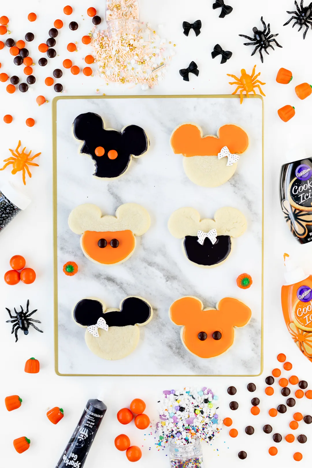 Mickey and Minnie Halloween Cookies decorated with orange and black icing and candies.
