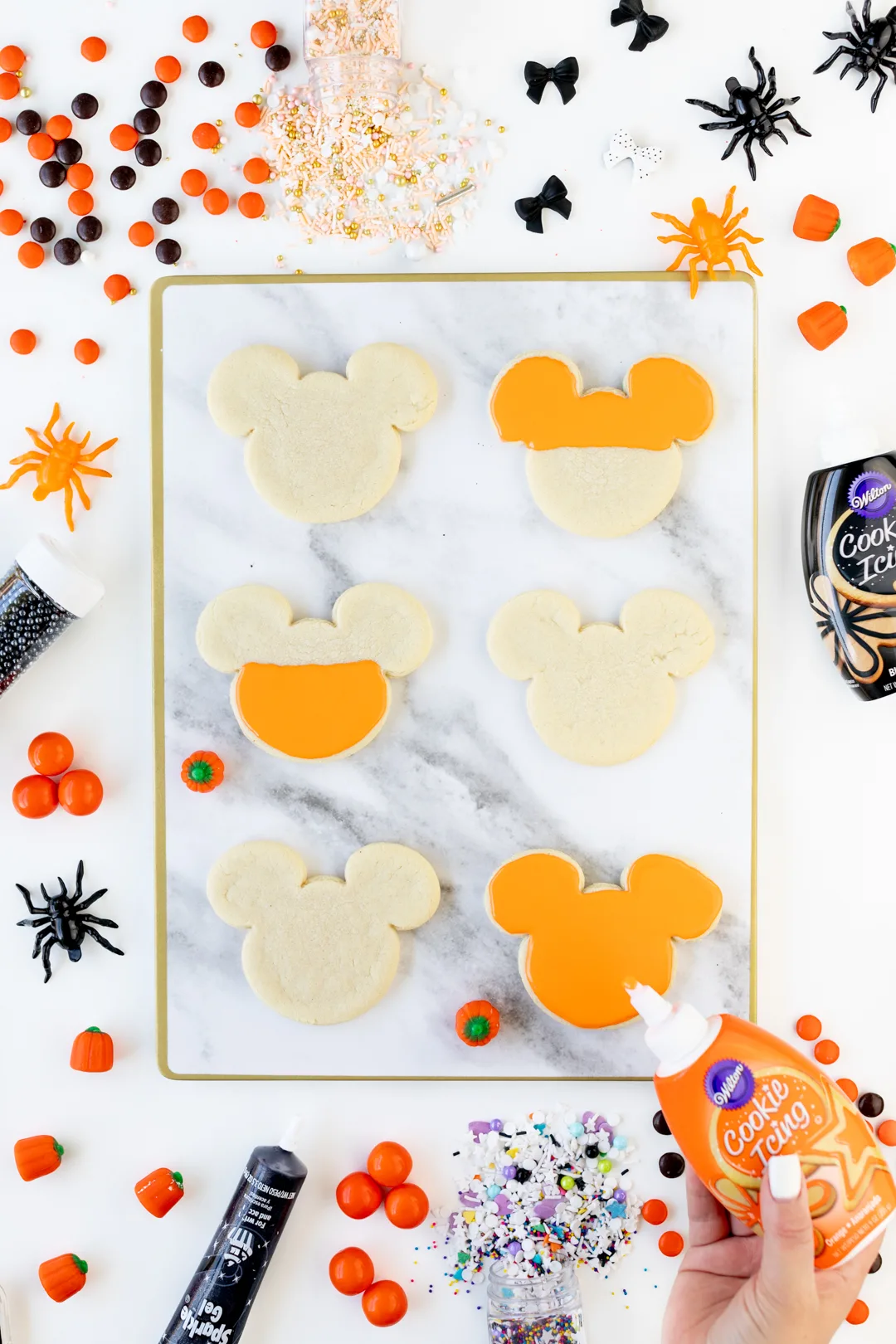 Adding orange icing to mickey mouse shaped cookies.