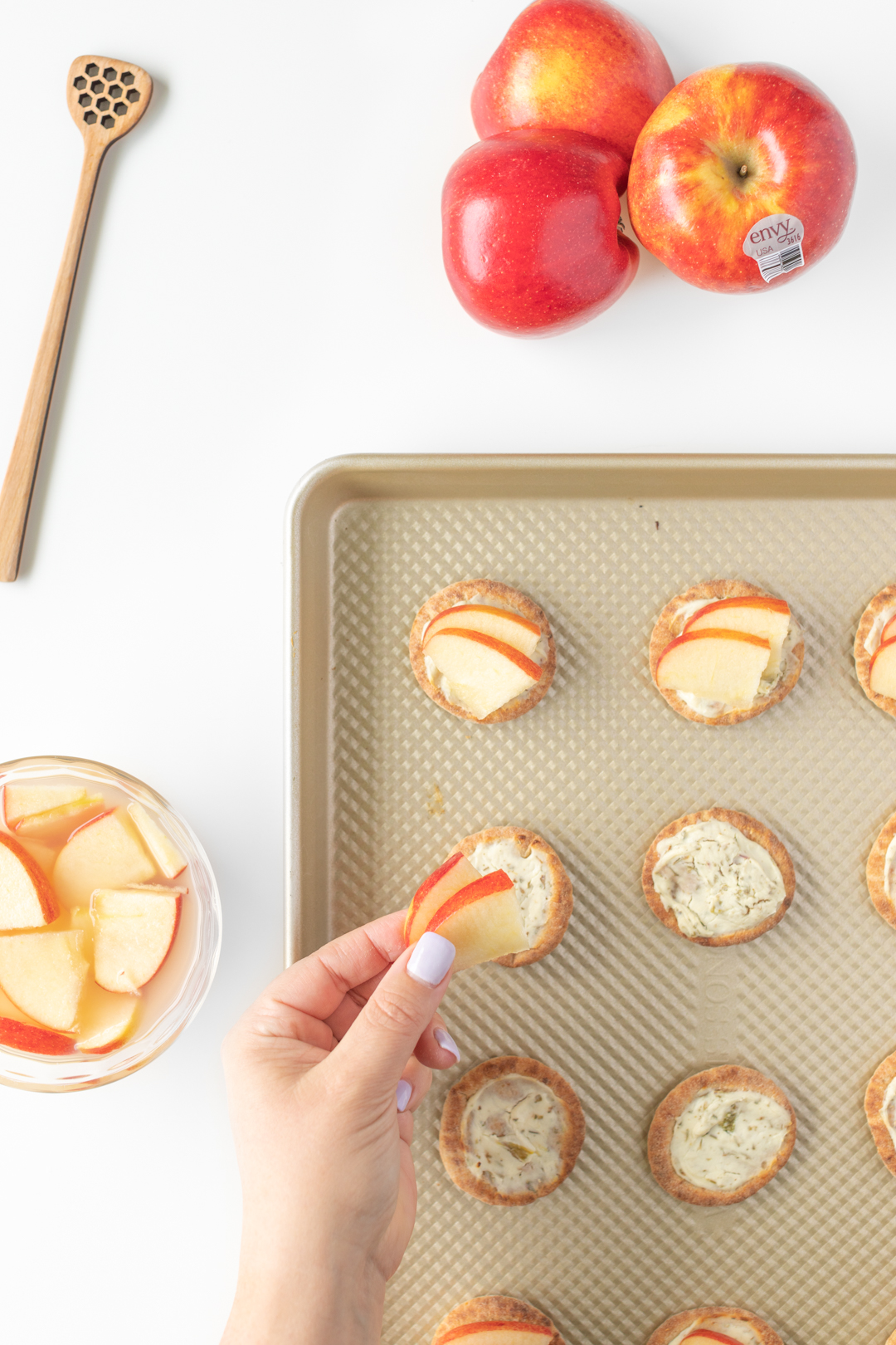 adding small slices of apples to mini pita appetizers