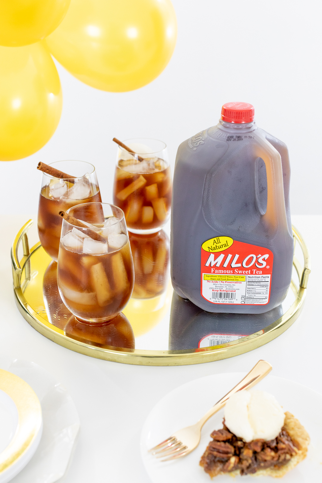 Serving tray with iced tea in glasses with cinnamon stick garnish.