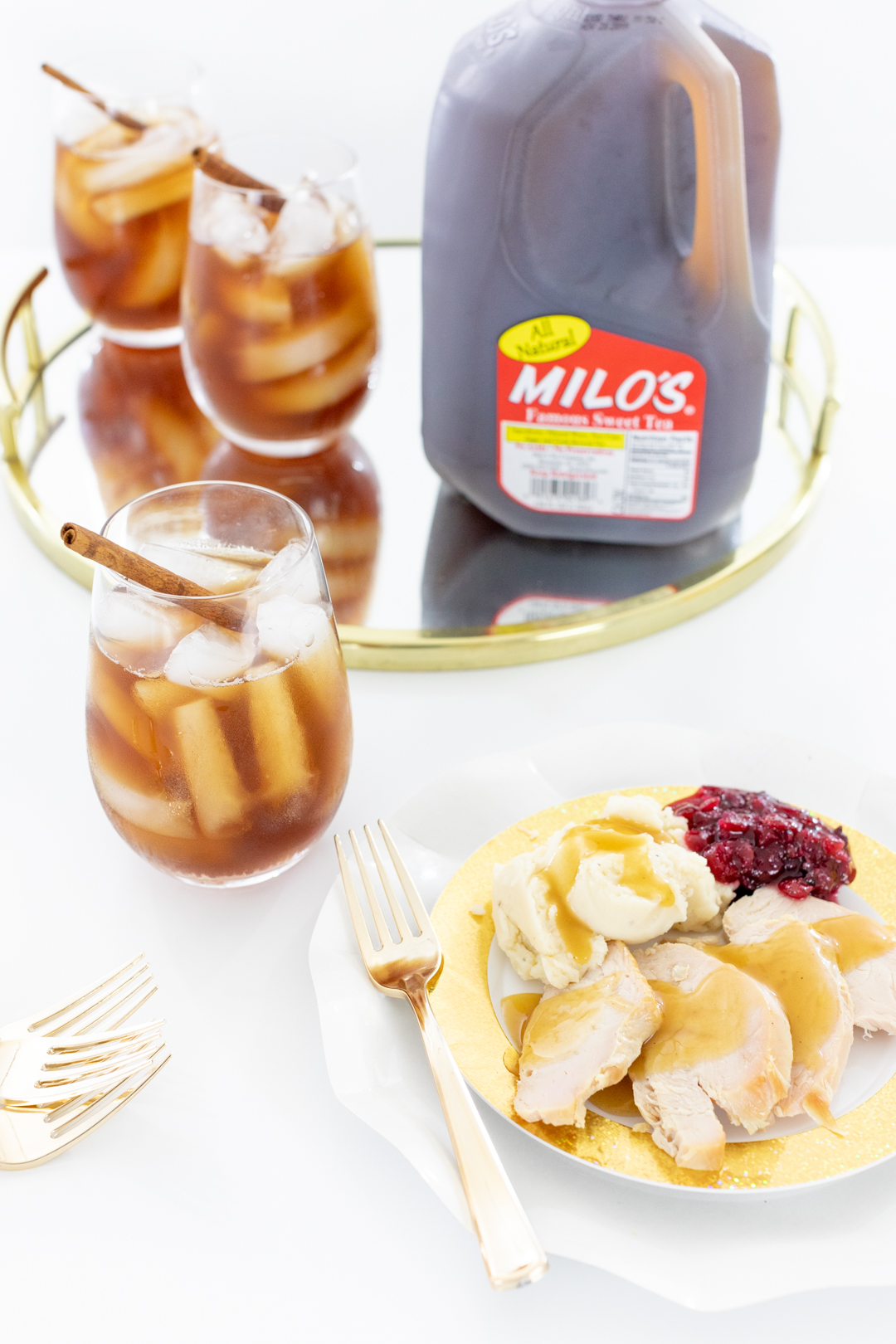 Thanksgiving dinner plate with turkey, mashed potatoes, gravy, cranberry sauce served with iced tea.