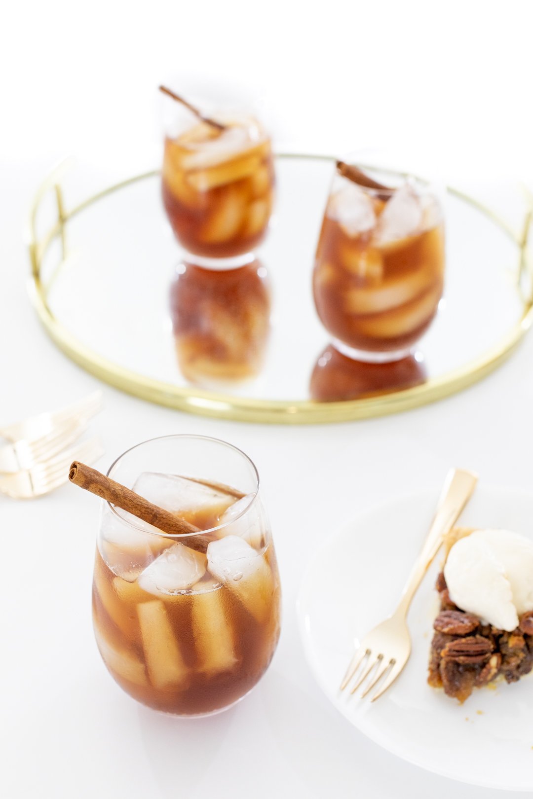 Glass of iced tea with ice and a cinnamon stick served with a slice of pecan pie with ice cream.