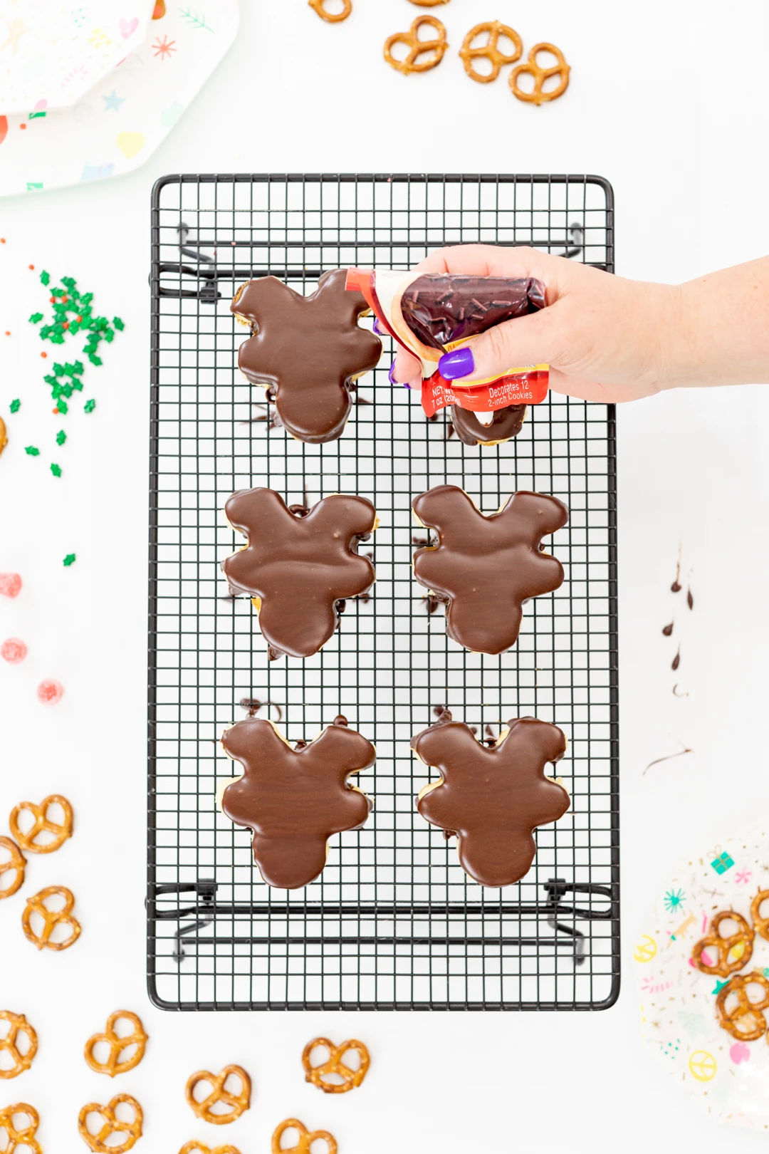 Using chocolate cookie icing to decorate mini reindeer cakes.