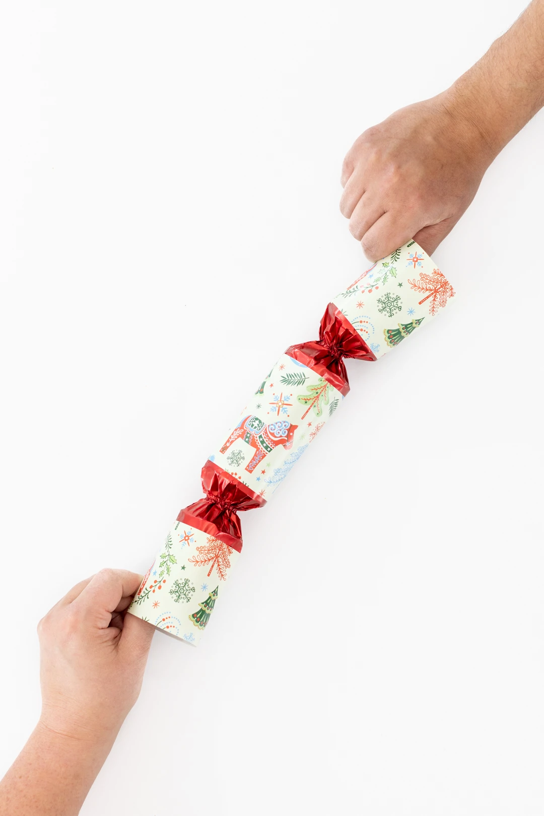 Two people tugging at a Christmas Cracker to demonstrate how to make it pop.