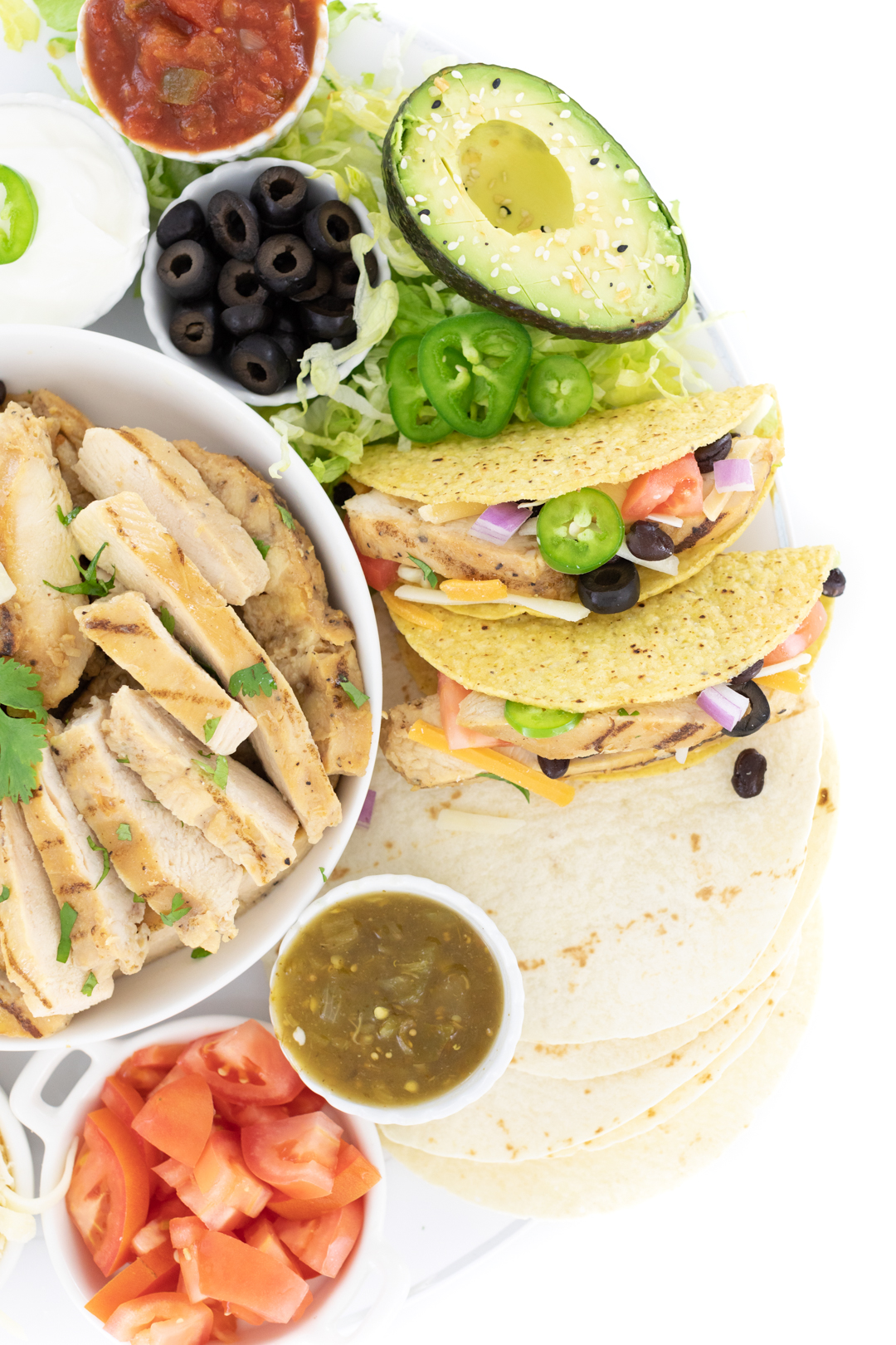 taco spread with grilled chicken strips, avocado, salsa tomatoes, shredded lettuce