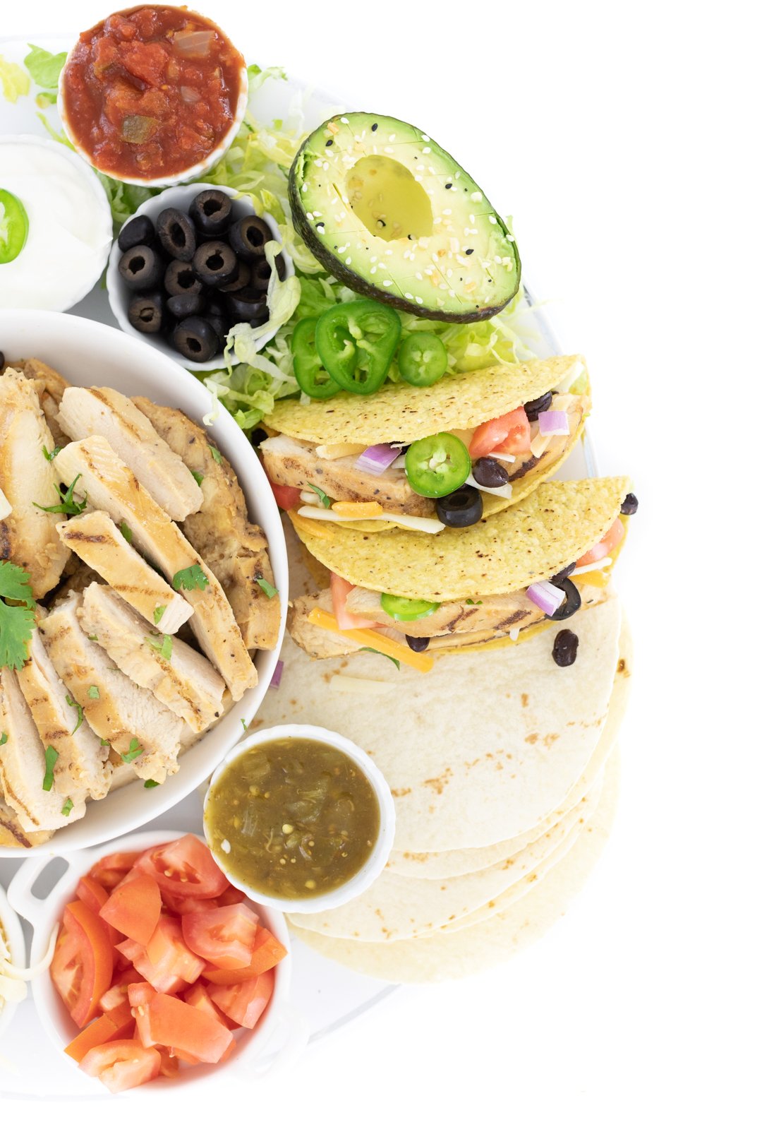 taco spread with grilled chicken strips, avocado, salsa tomatoes, shredded lettuce