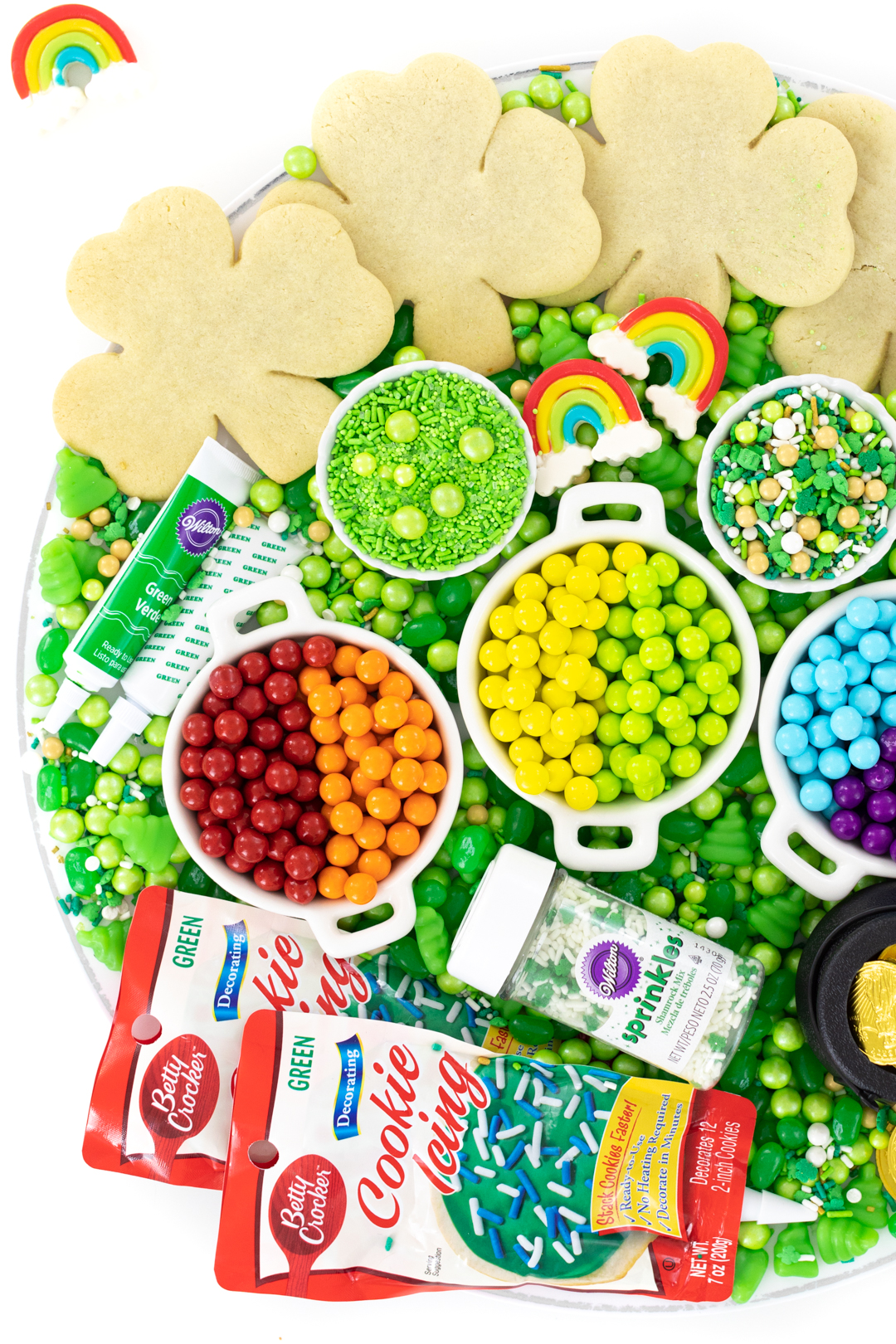 tray of unfrosted shamrock cookies and sprinkles and toppings