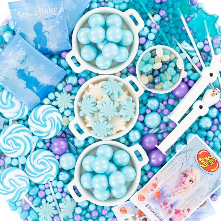 candy board with blue gumballs, snowflake gummy candies, swirl lollipops and olaf pez dispensers