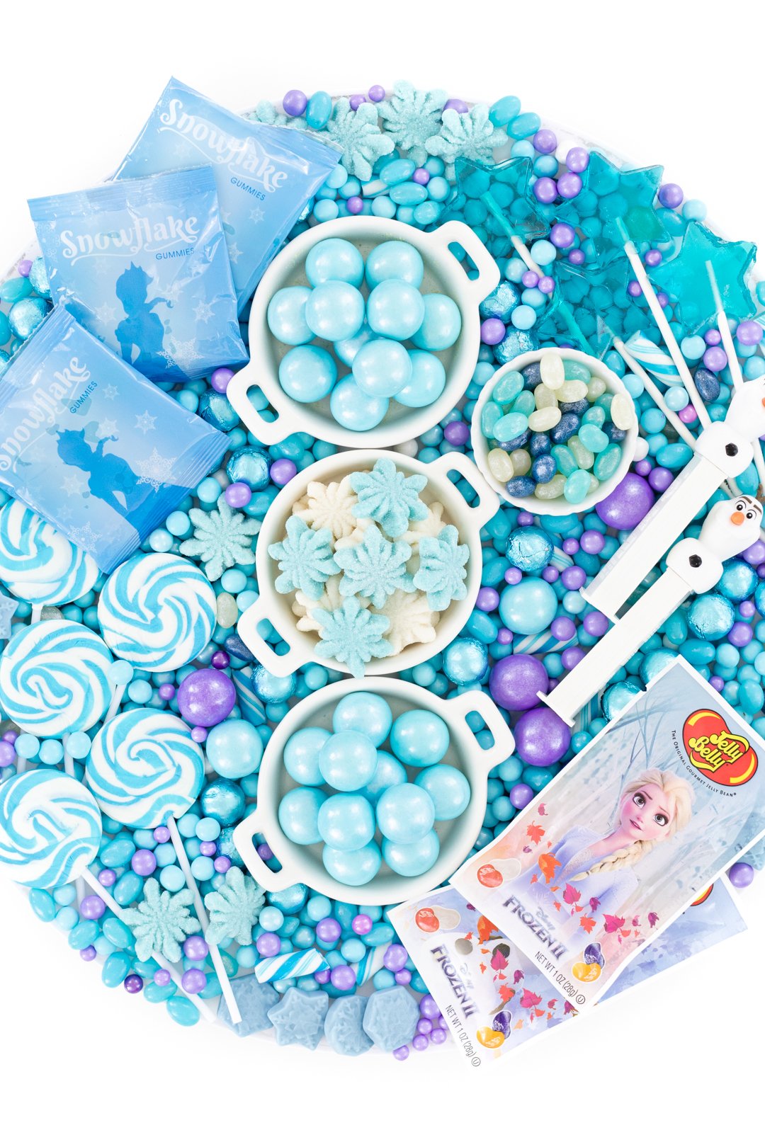 candy board with blue gumballs, snowflake gummy candies, swirl lollipops and olaf pez dispensers