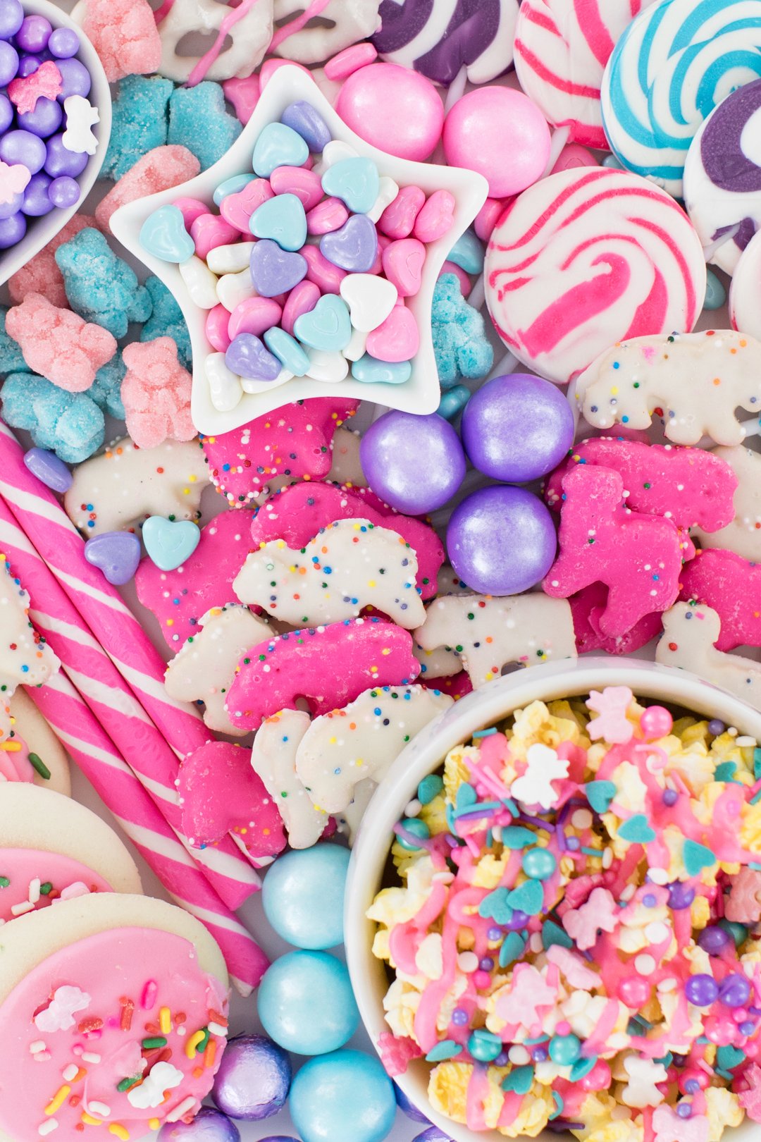 Tray filled with pastel candies, gumballs, cookies, pastel popcorn.