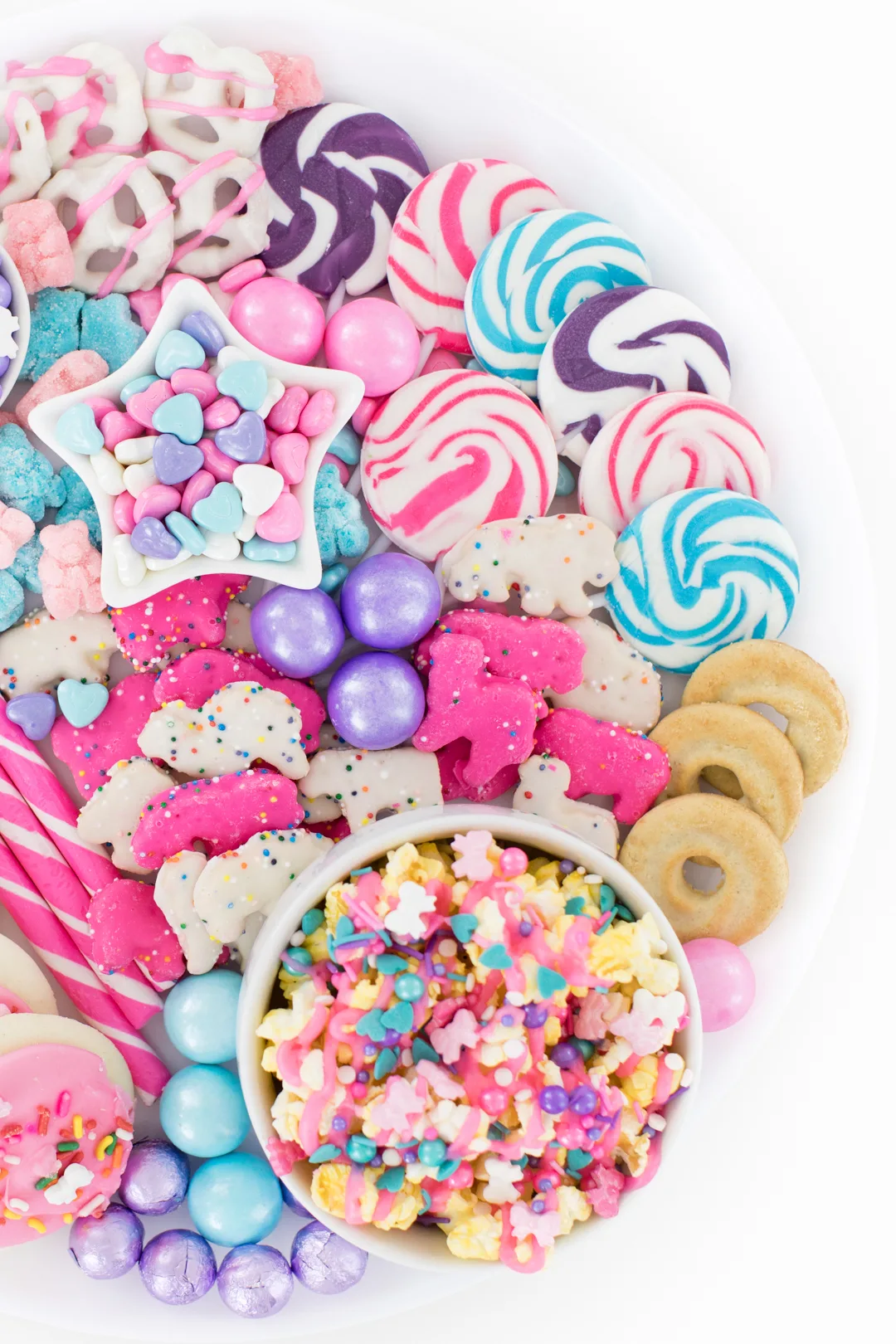 pastel snack board with lollipops and popcorn and cookies.
