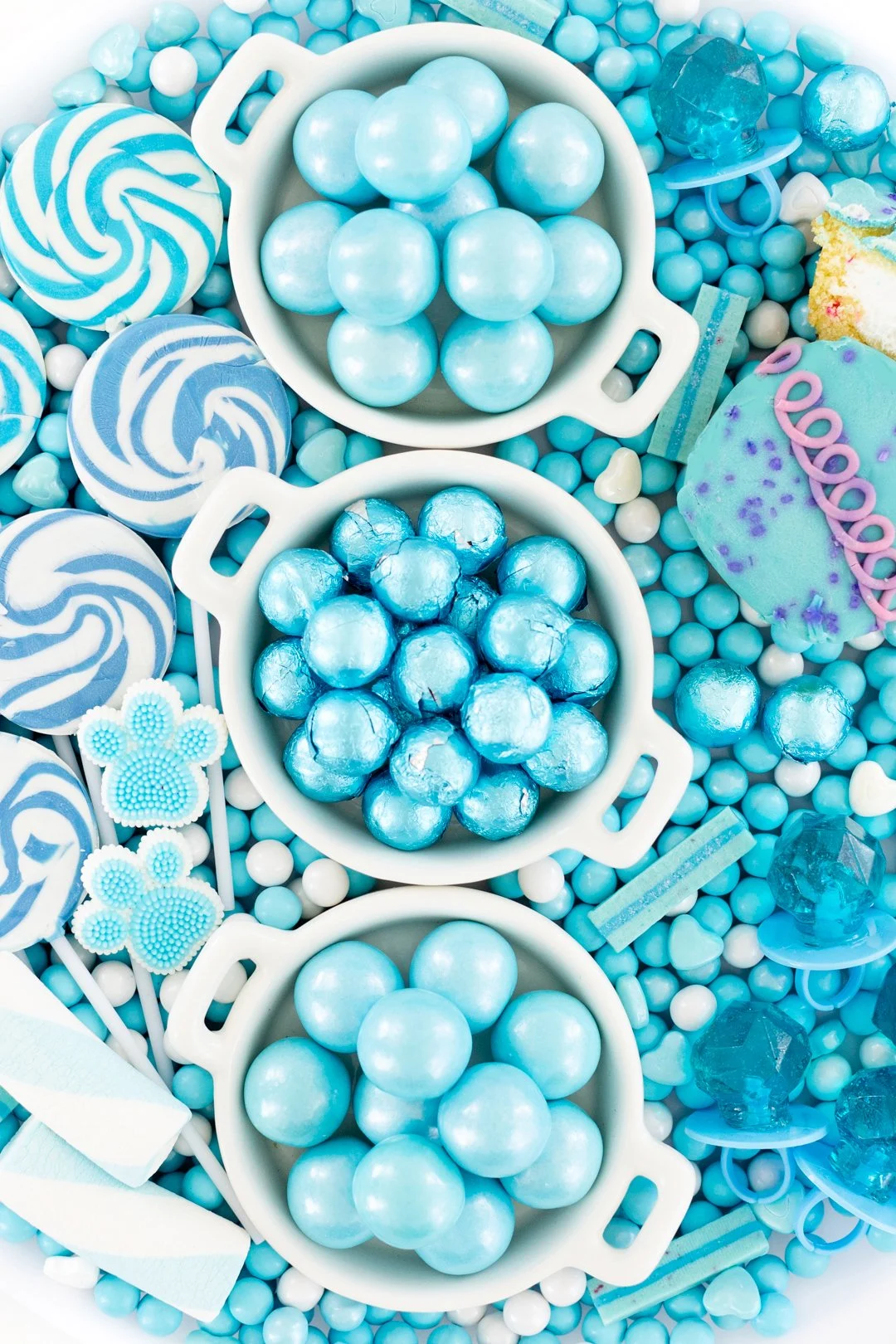 candies. Blue foil wrapped chocolates, gumballs, lollipops on a tray.