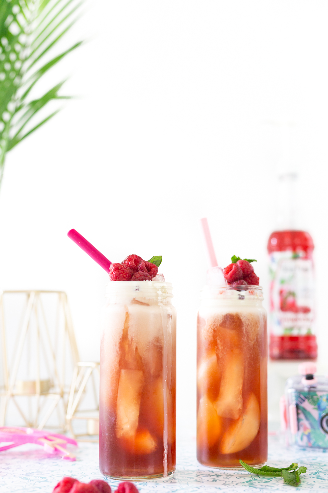 Pretty iced tea for summer with raspberries and pretty pink straws