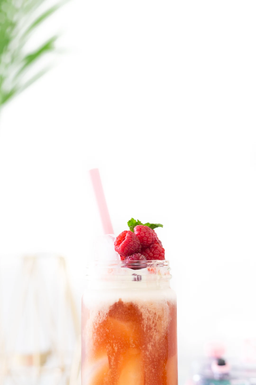 glass of iced tea with fresh raspberries and mint on top
