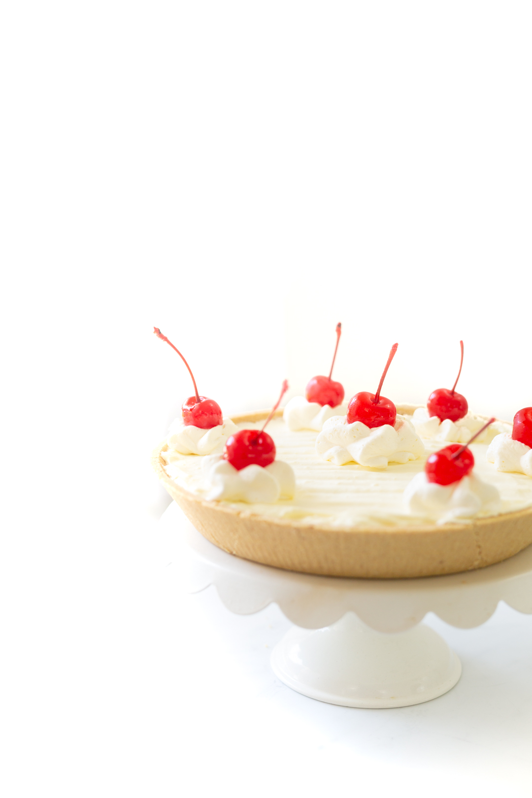 pretty pineapple pie with large cherries with stems on top to decorate