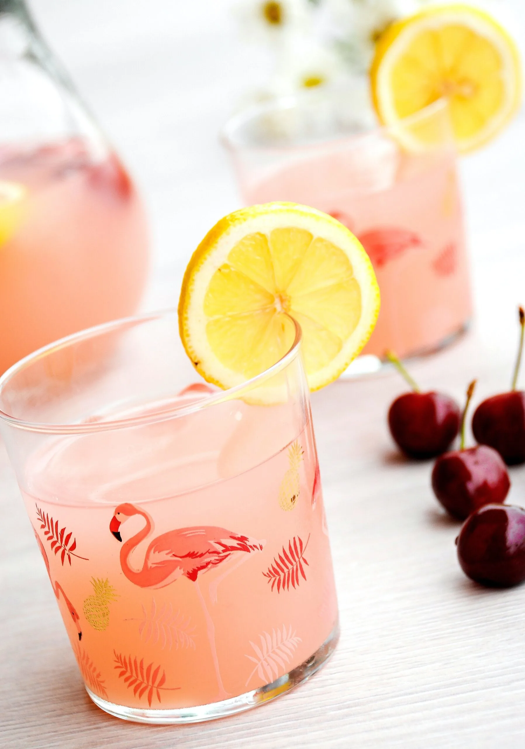 flamingo glasses filled with pink beverage and lemon wedge
