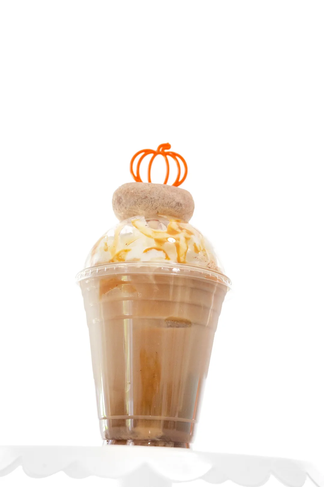 fancy pumpkin iced coffee with mini donut on top and pumpkin stirrer