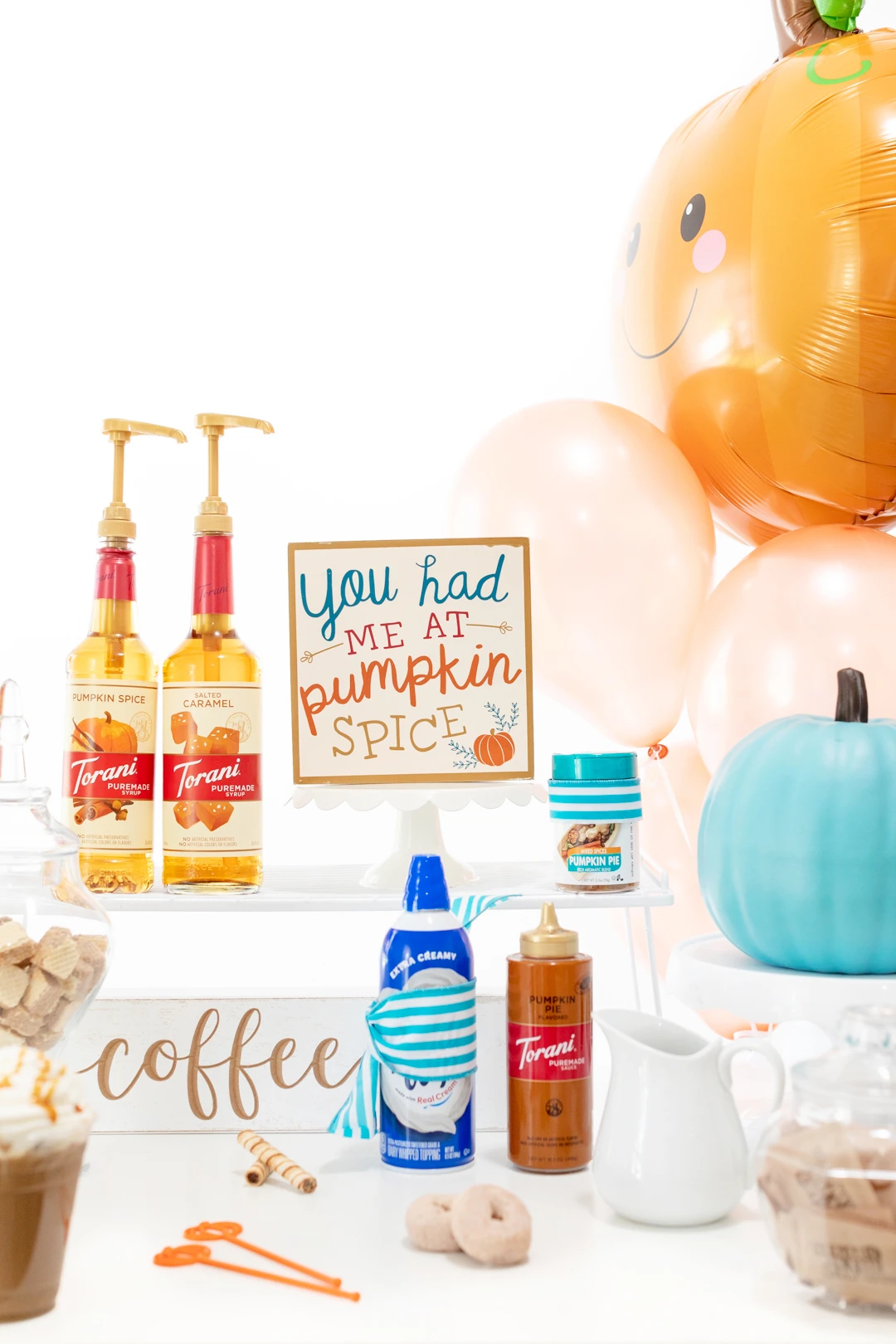 pretty iced coffee bar with syrups, signs, whipped cream, sauces and balloons to decorate.