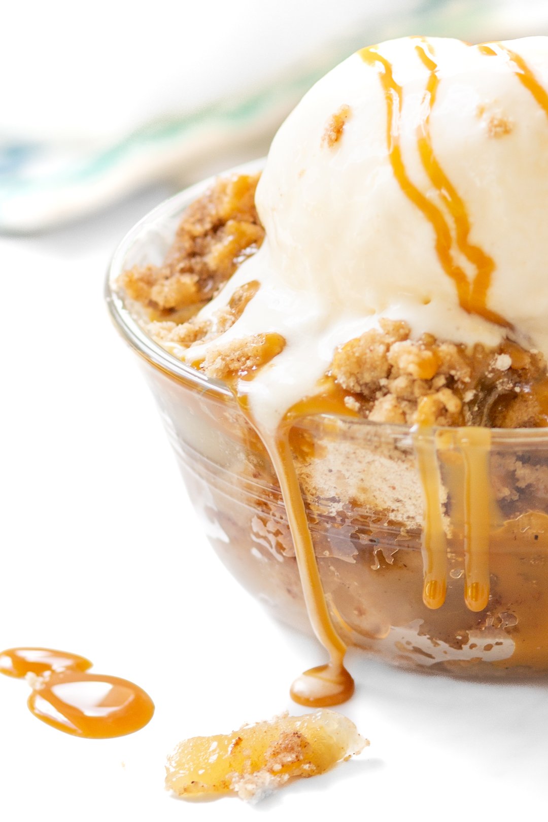 apple dump cake up close with apples and cake crumbs topped with ice cream and caramel