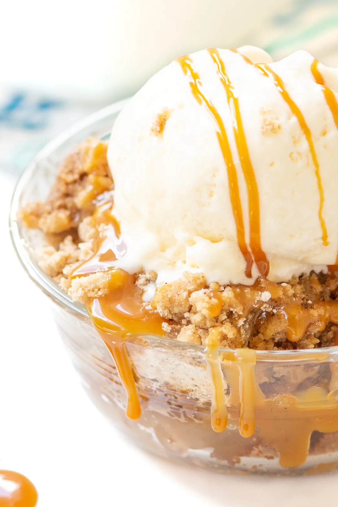 bowl of apple dump cake with oozing caramel and melty ice cream on top.