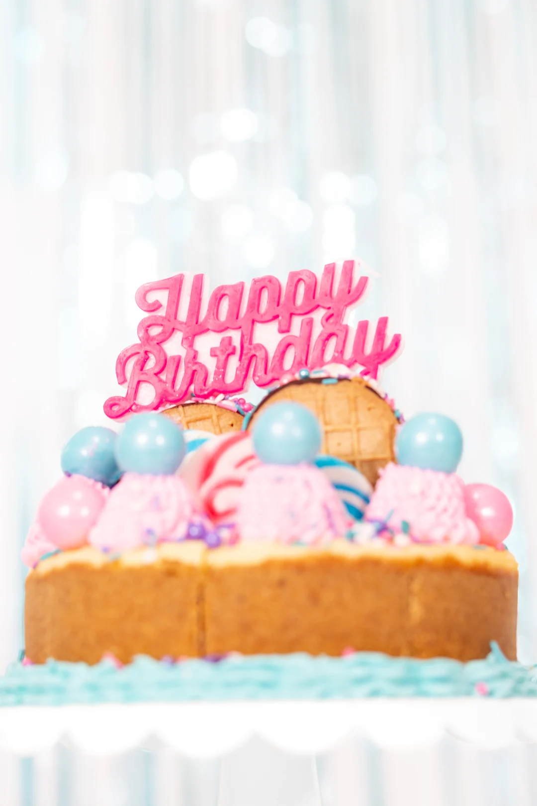 pretty birthday cheesecake with pink and blue cake toppings from lollipops to gumballs