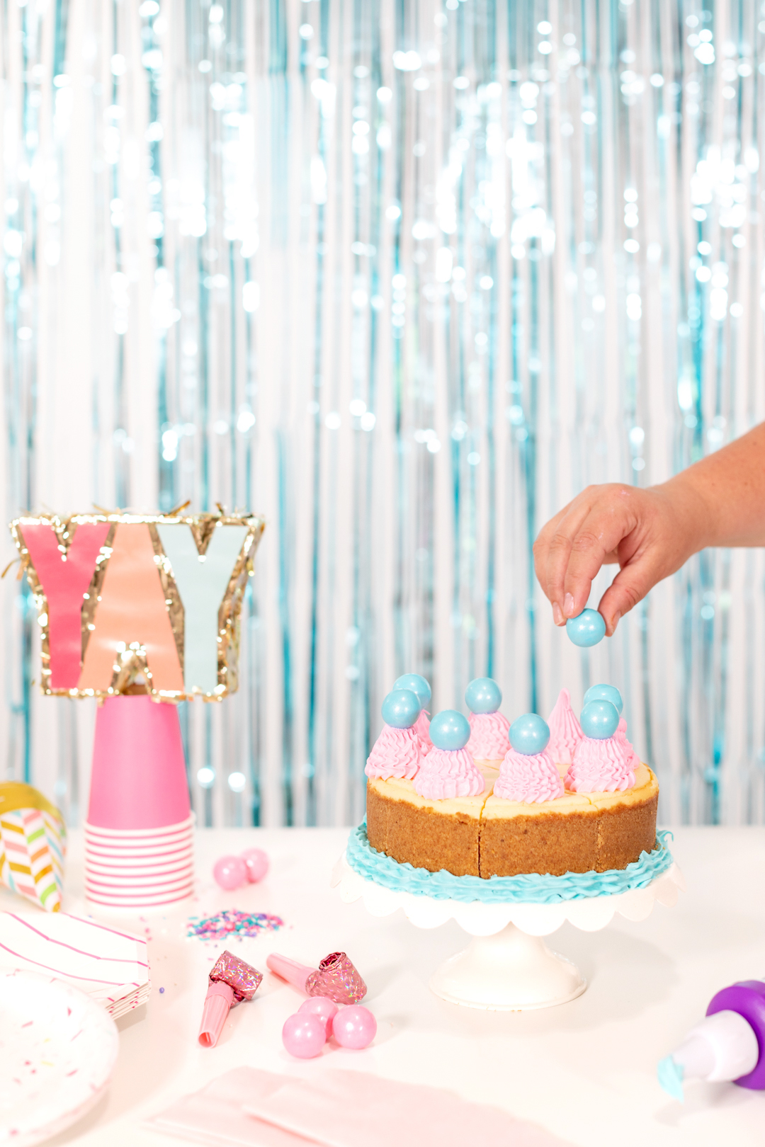 Adding gumballs to frosting peaks on a birthday cake