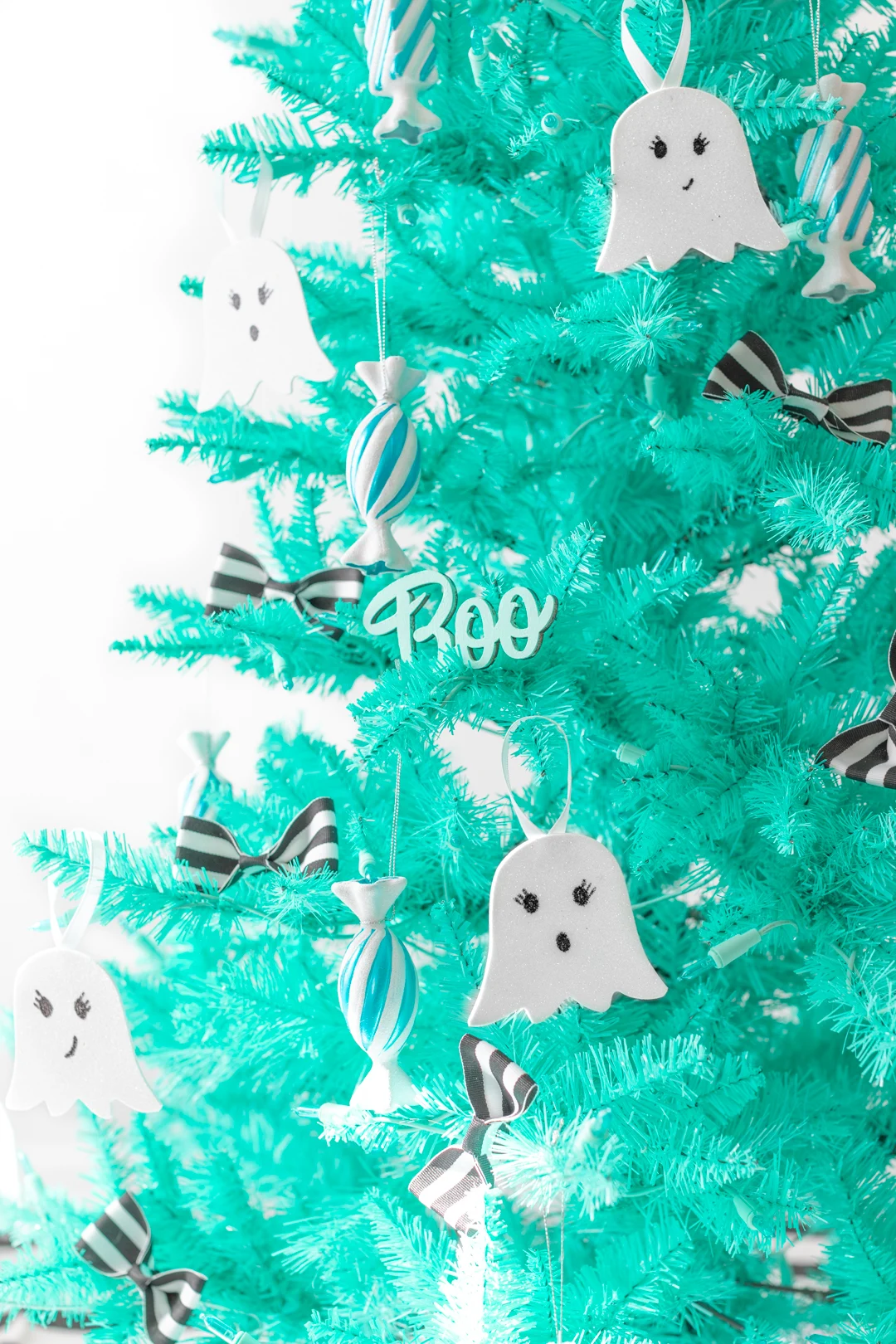teal christmas tree decorated for halloween with ghost ornaments and candy ornaments