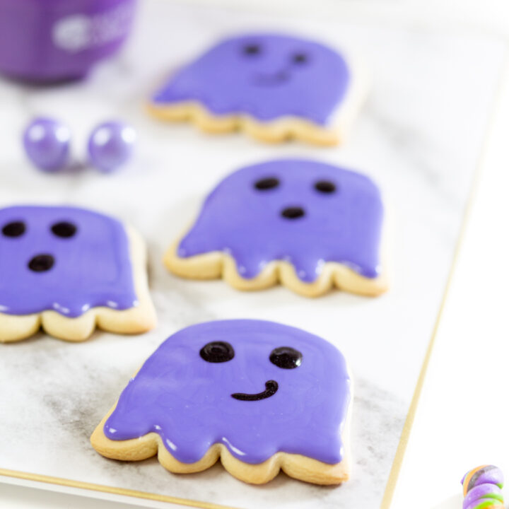 purple ghost cookies on a tray, freshy iced with purple cookie icing