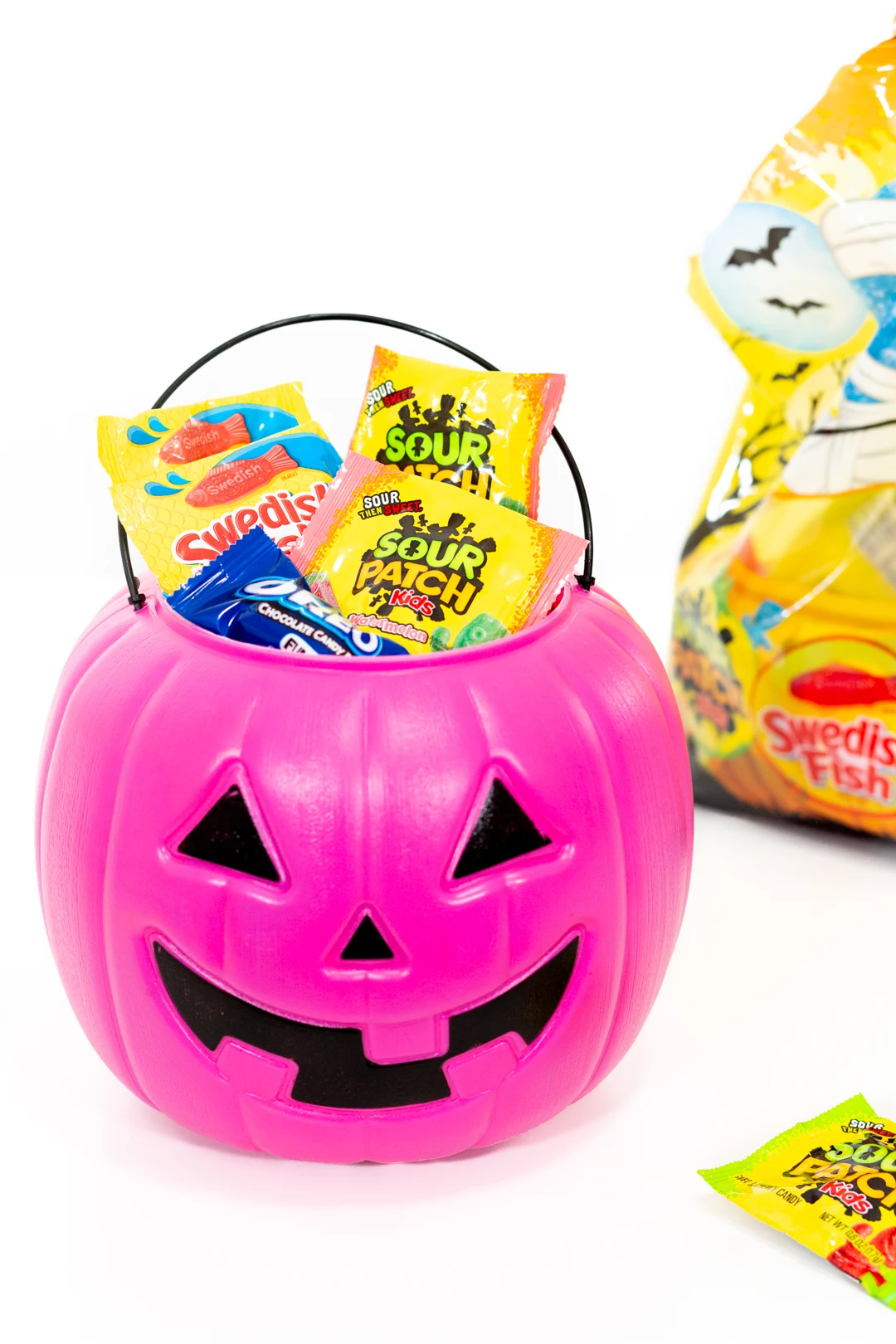 pink jack o'lantern halloween candy basket filled with swedish fish, sour patch kids and oreo candy bars 