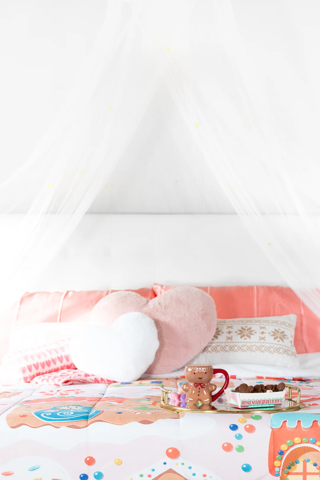 cozy christmas bedroom setup with heart-shaped pillows, gingerbread blankets and pretty tent.