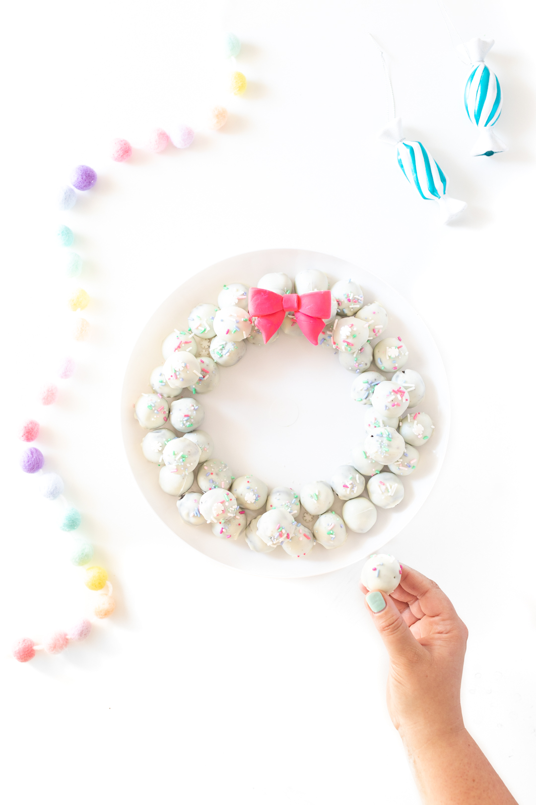 woman picking up an oreo cookie ball from a holiday tray