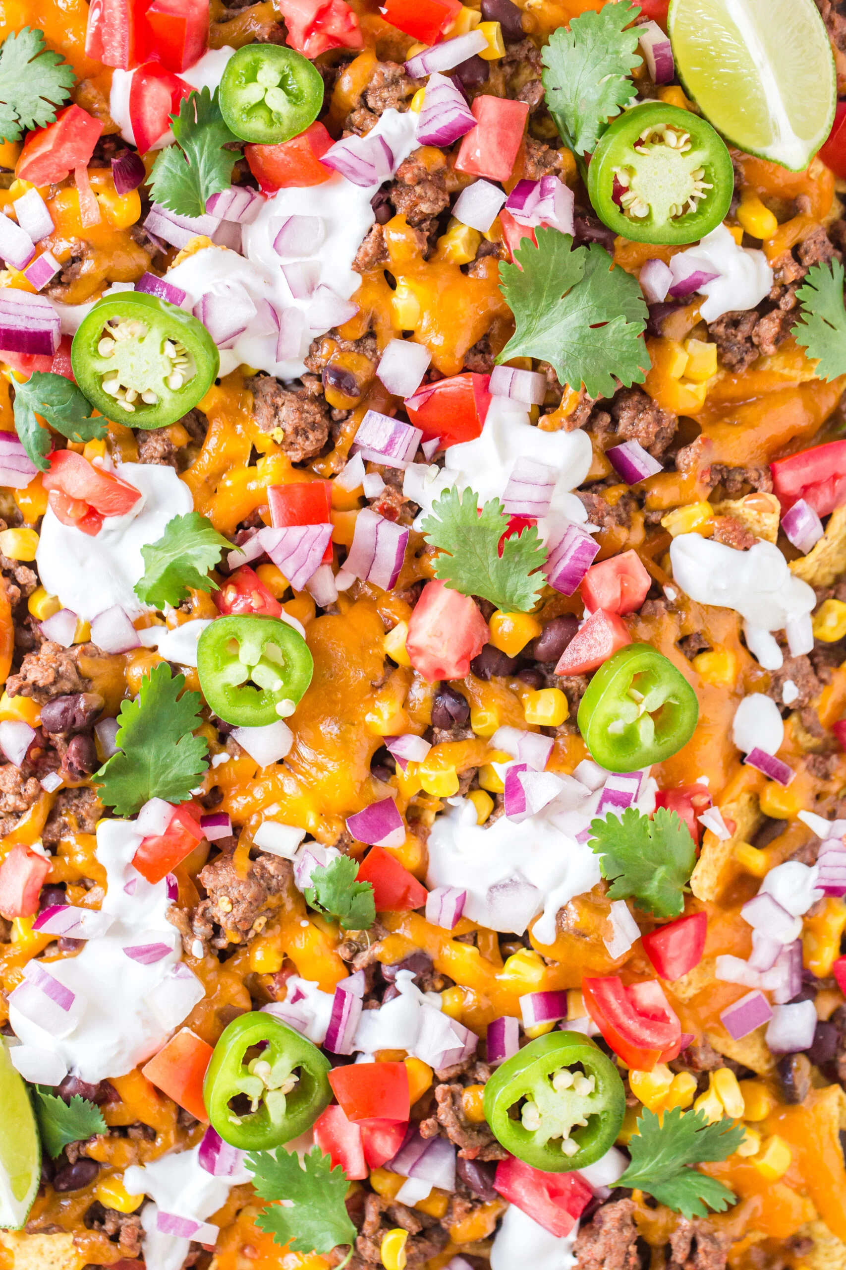 up close view of a sheet pan filled with nachos and generous toppings