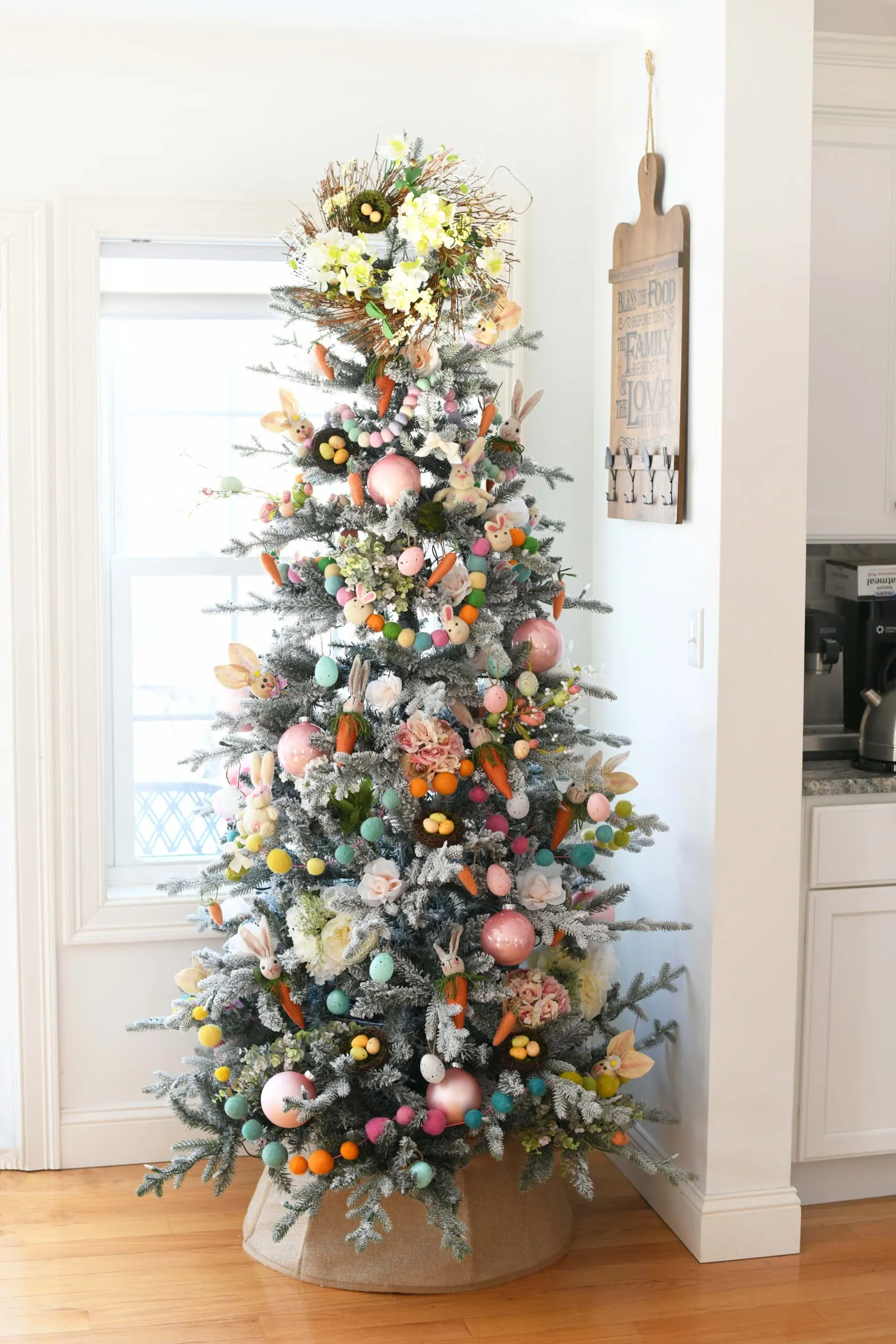 pretty farmhouse style christmas tree decorated for easter with large pom pom style garlands and pretty light easter toned decorations