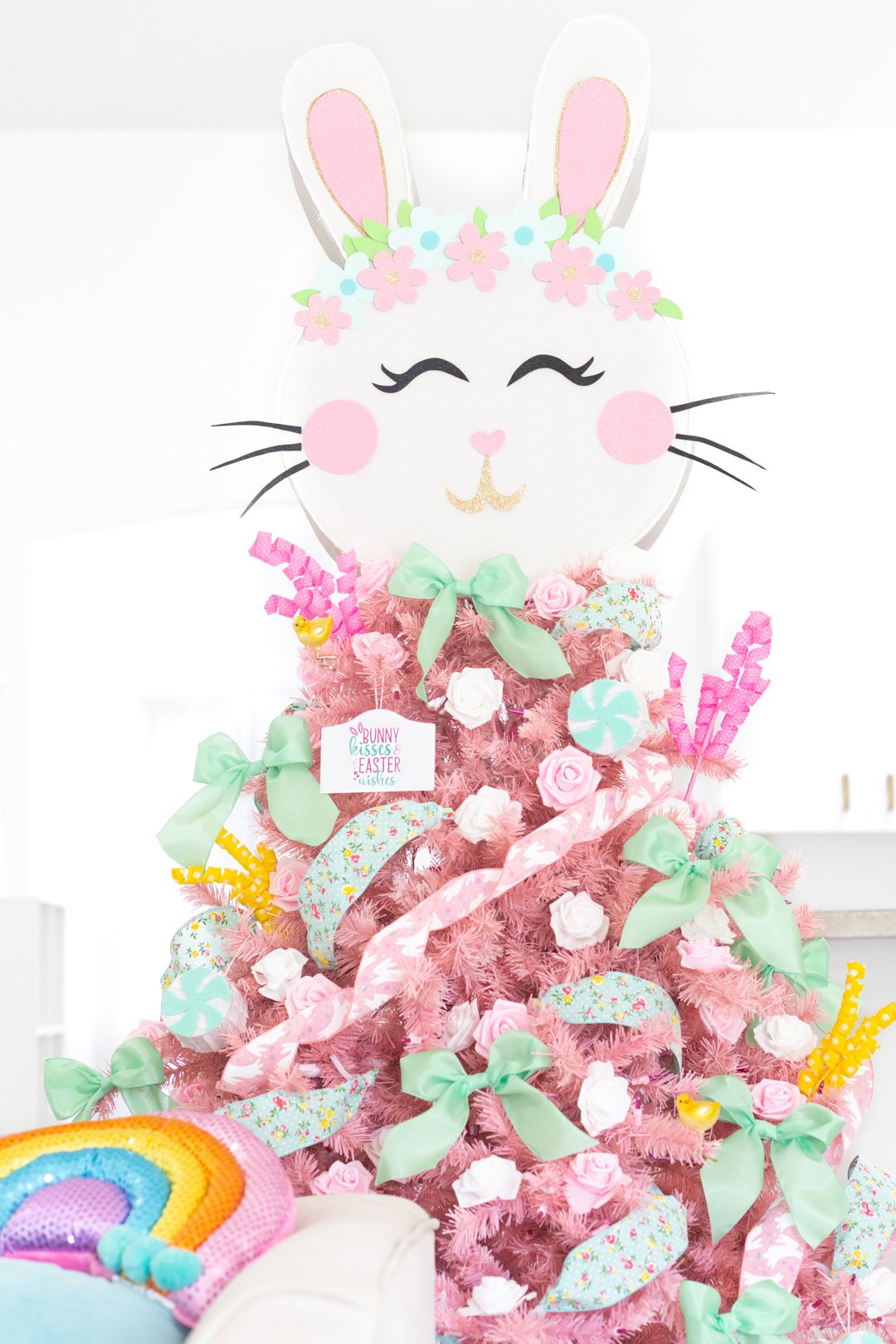 pretty pastel easter christmas tree. light pink tree with variety of pastel decorations. mint colored bows. pink and white faux flowers. Pink bunny ribbon. Large bunny pinata tree topper.
