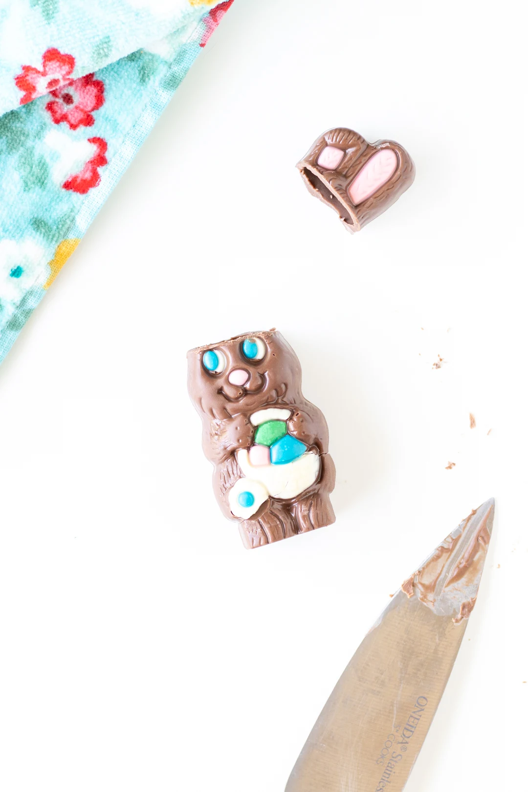 small hollow chocolate easter bunny with ears cut off. knife with melted chocolate on blade.