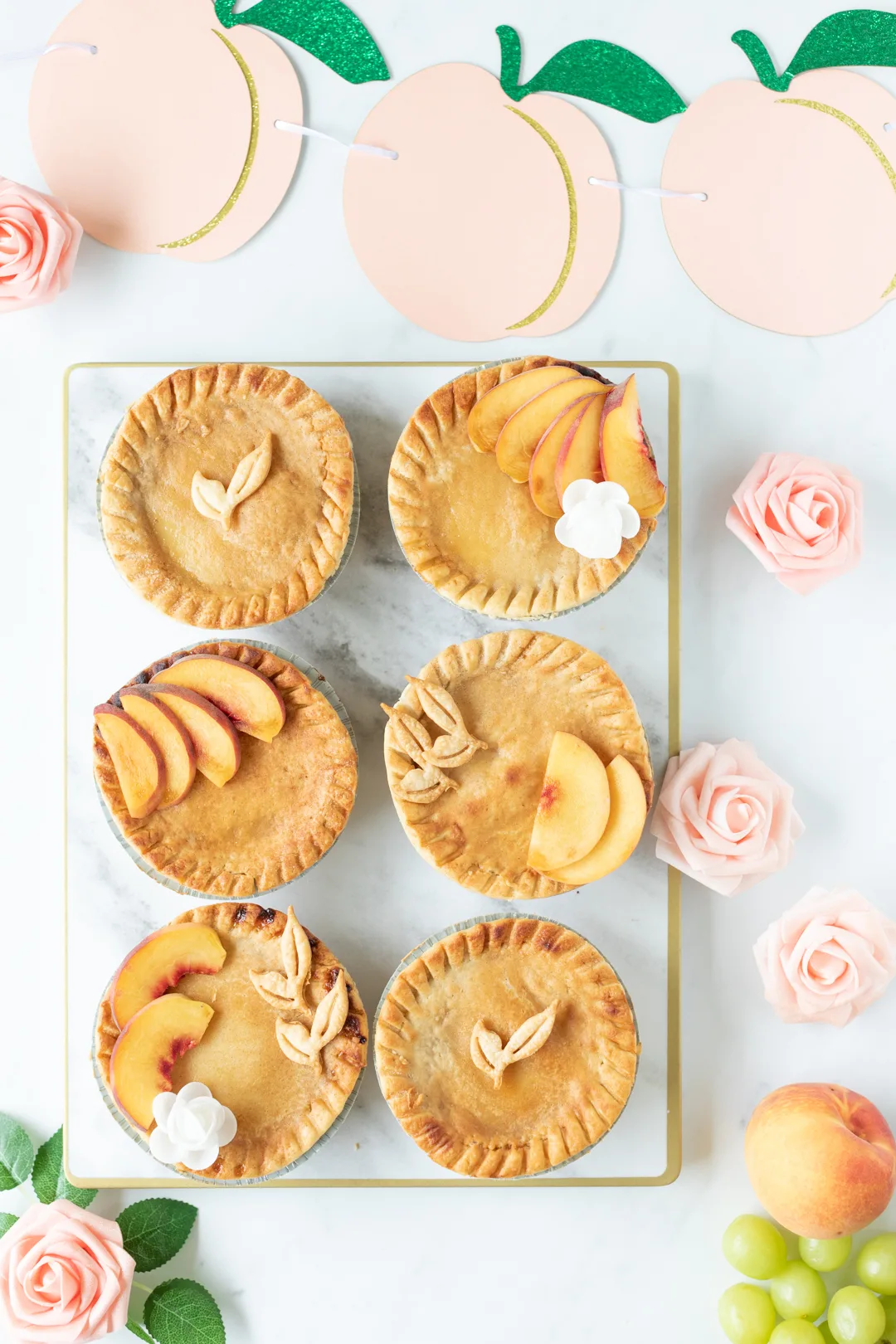 pies set out on a rectangular platter with peach colored decorations like faux flowers and peach banner.