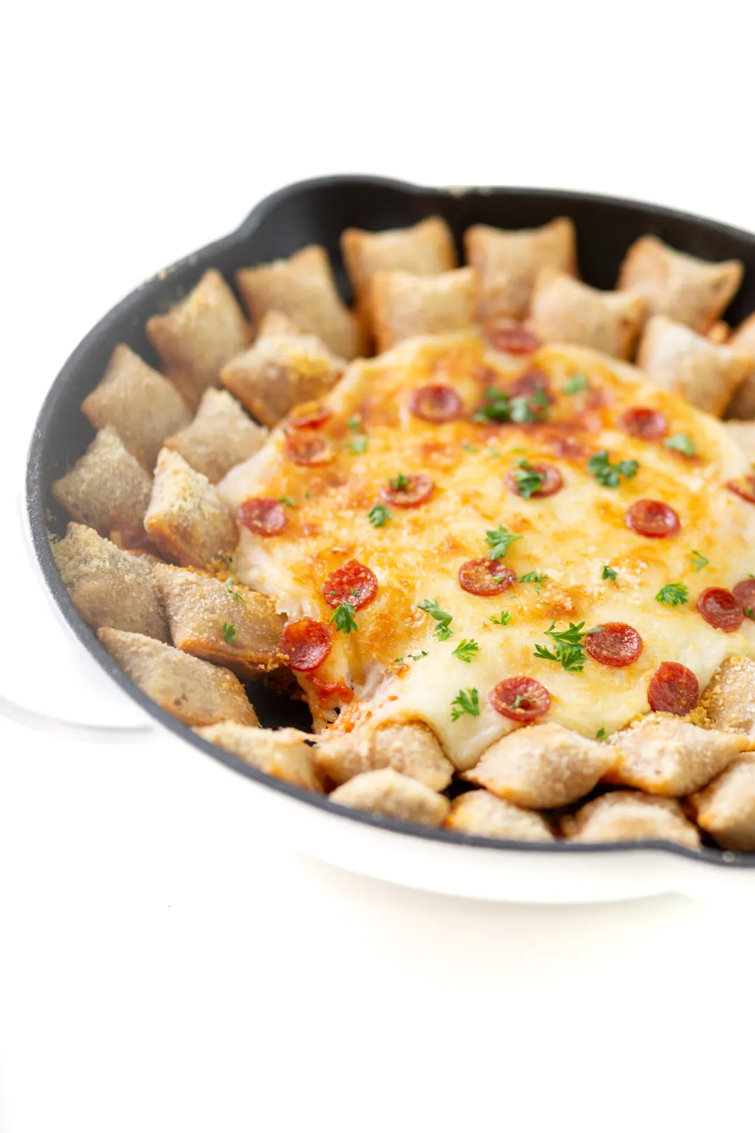 pepperoni pizza roll skillet dip with one pizza roll eaten to reveal the cheesy goodness inside the skillet