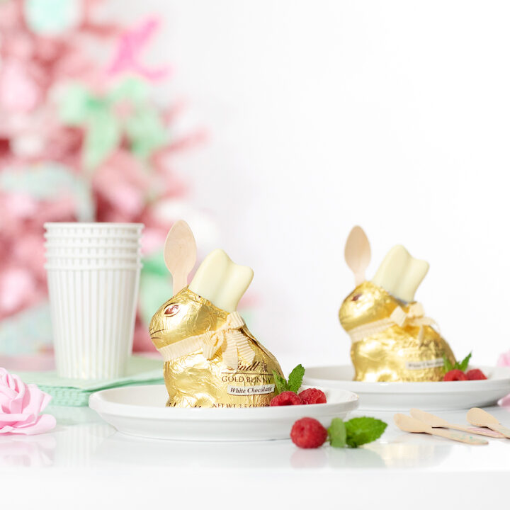 cute easter desserts. individual trifles inside of lindt white chocolate bunnies. pink easter tree in the background. pretty pink faux roses as tablescape decor