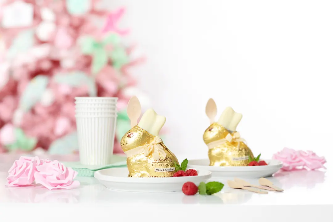 cute easter desserts. individual trifles inside of lindt white chocolate bunnies. pink easter tree in the background. pretty pink faux roses as tablescape decor