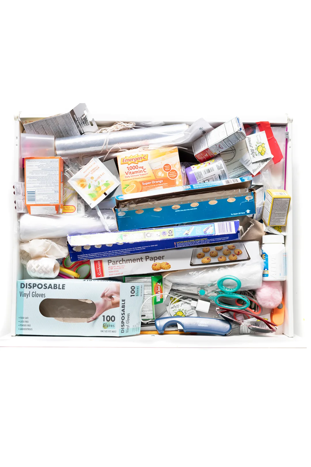messy junk drawer with a variety of random items stuffed into from medicines to foil.