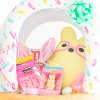 up close pastel easter basket with yellow stuffed bunny with pink glasses, pink peeps and a white chocolate hollow bunny