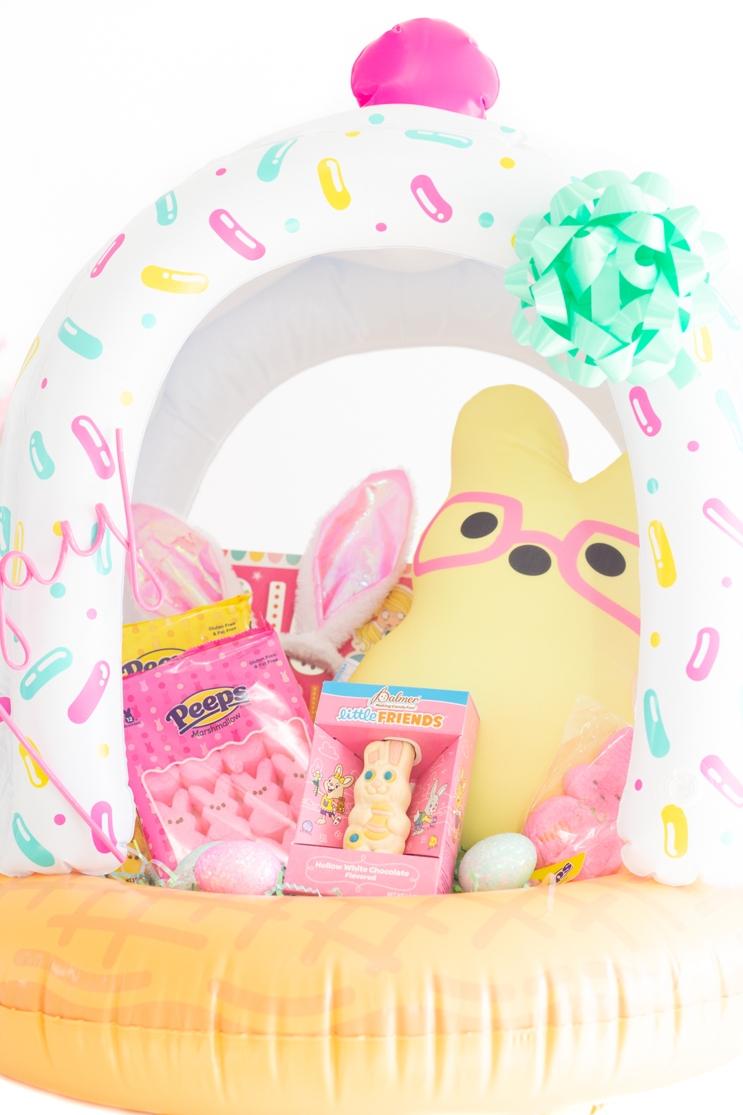 up close pastel easter basket with yellow stuffed bunny with pink glasses, pink peeps and a white chocolate hollow bunny