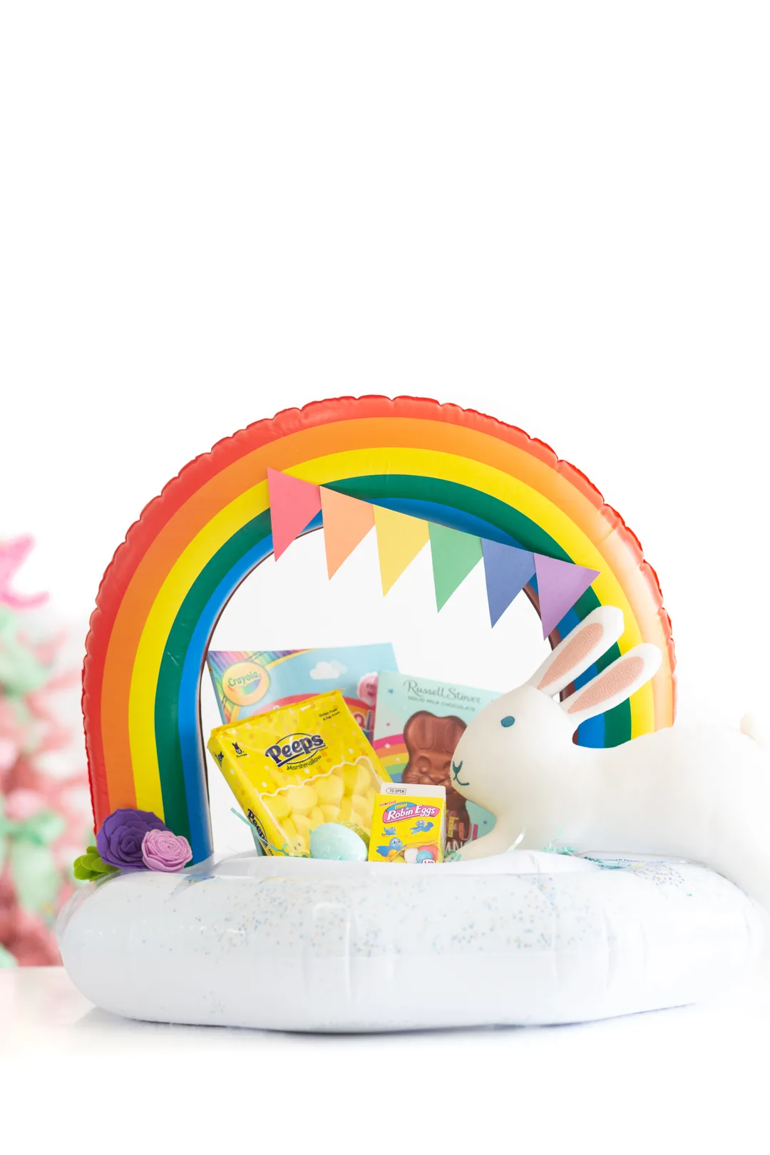 Rainbow pool float filled with Easter basket fillers like Peeps, Easter Candies, Coloring Books and Chocolate.