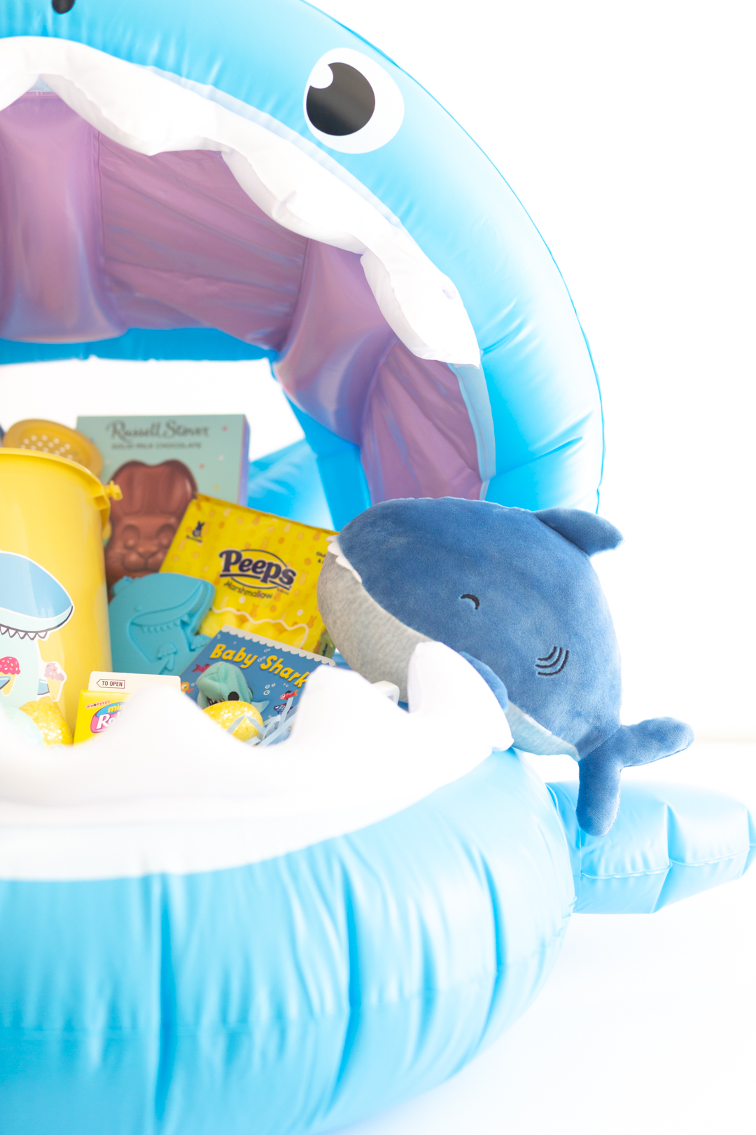 inside view of a shark themed gift basket with shark plush, shark pail set, shark book, peeps, easter bunny