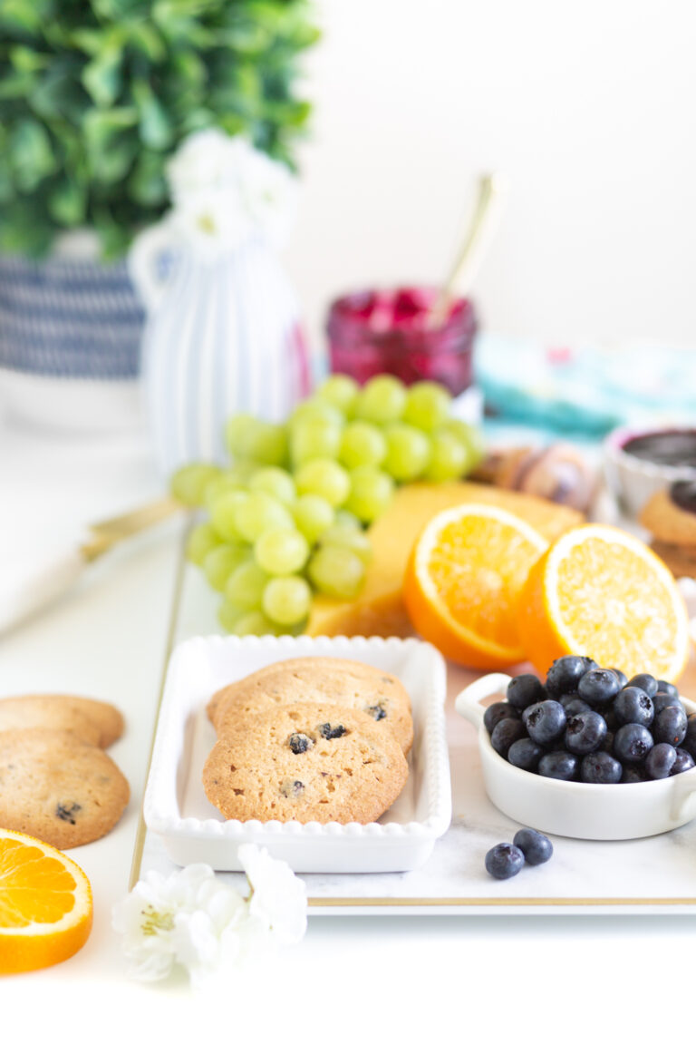 up close of a brunch board with crispy blueberry cookies and fresh fruits in the background