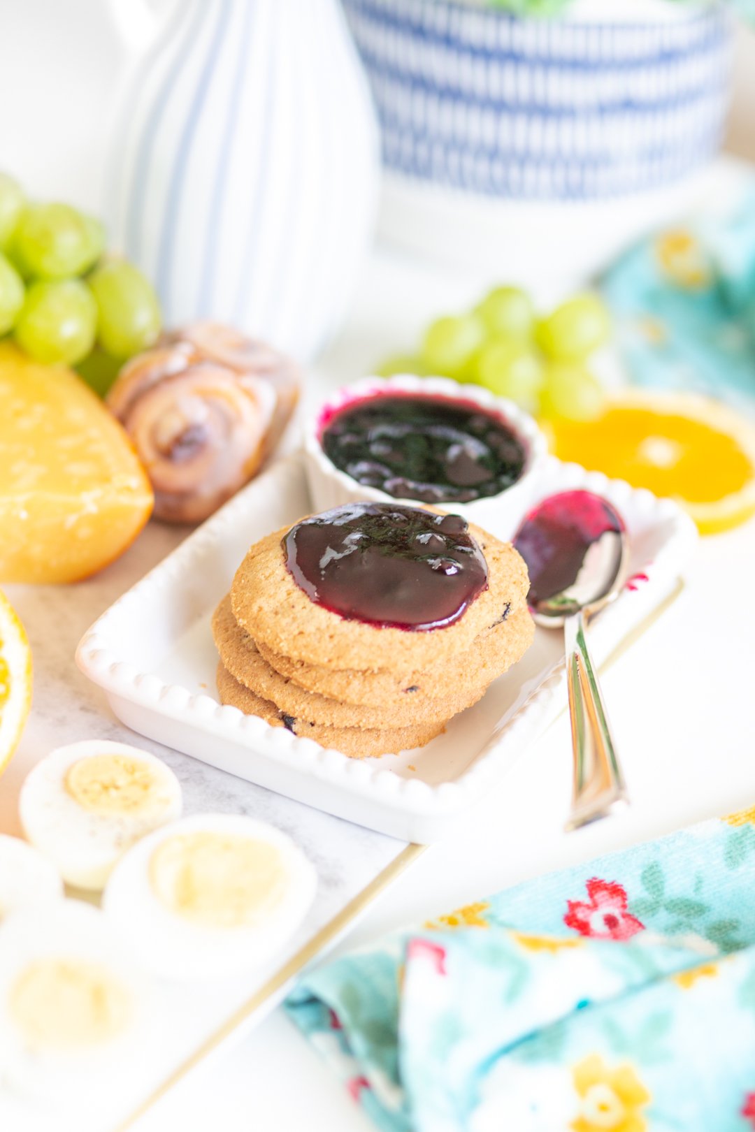 stack of blueberry cookies on a brunch tray topped with blueberry jam and a spoon with jam on it