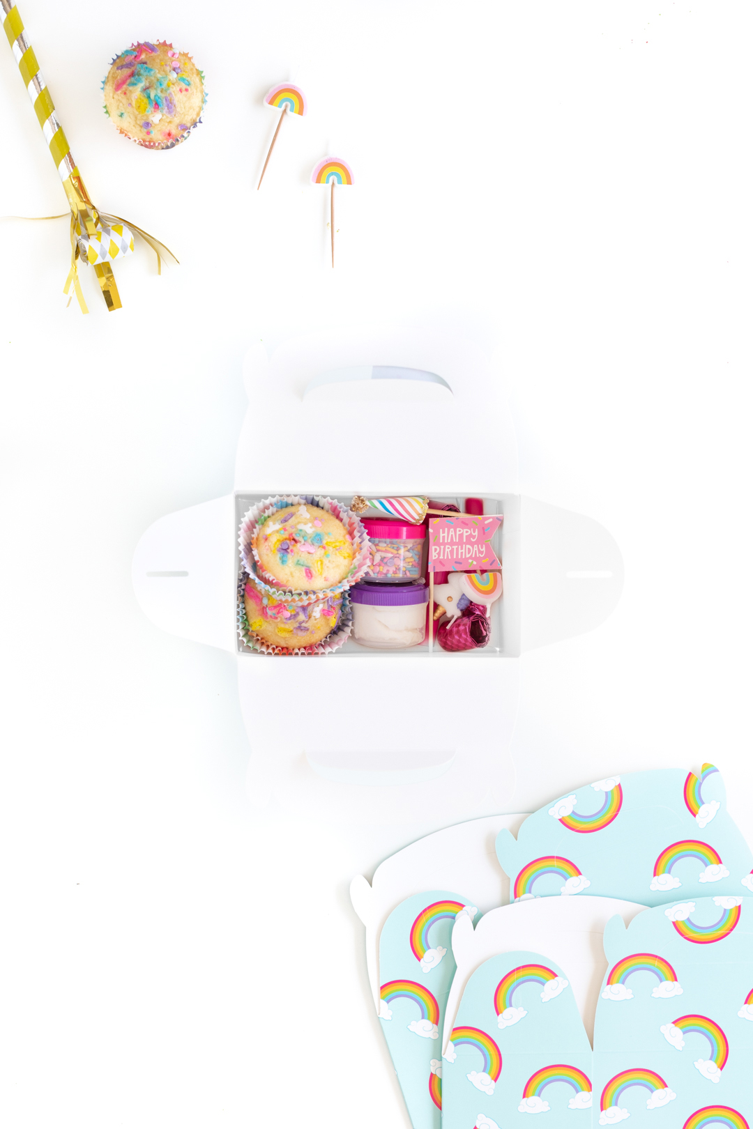 overhead view of a cupcake decorating kit filled with unfrosted cupcakes, sprinkles and cupcake toppers