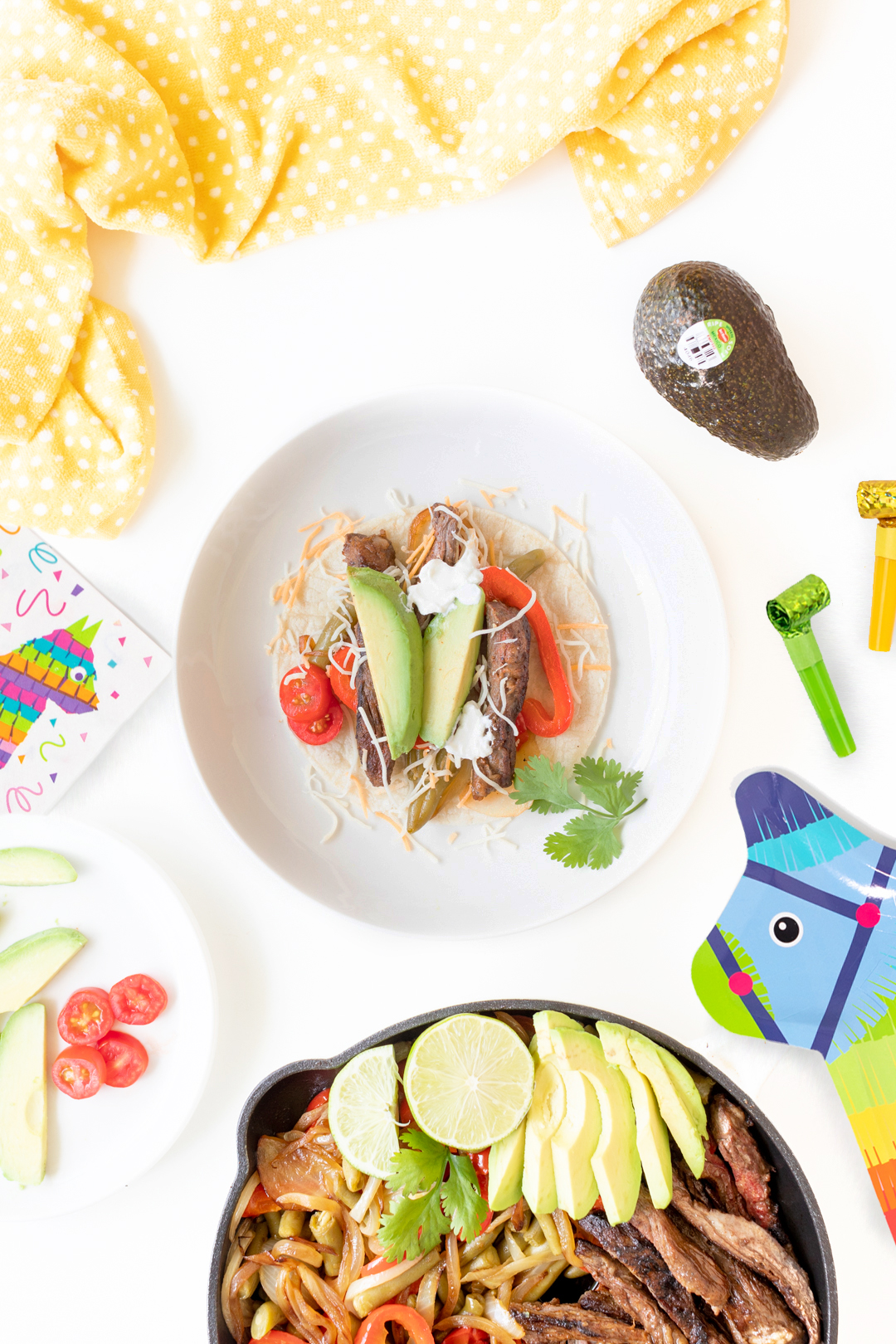 preparing a steak fajita on a plate topped with fresh avocado slices