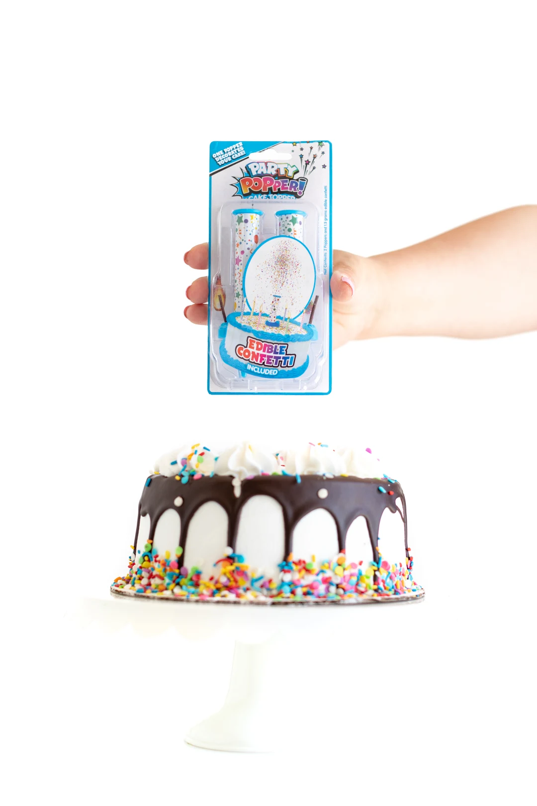 holding a package of party popper! cake topper candle placed on top of a white birthday cake with sprinkles and a chocolate drip.